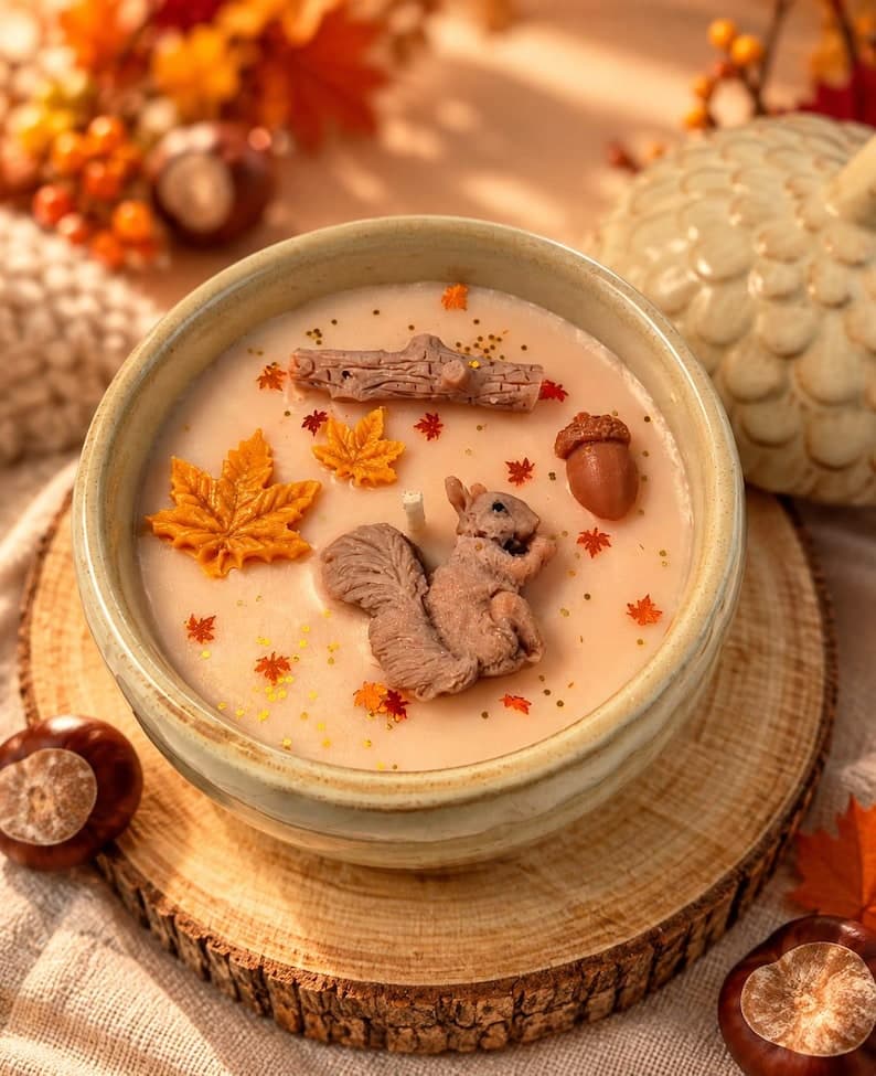 Herbstliche Duftkerze in einer runden Porzellanschale mit Eichel und Blättern